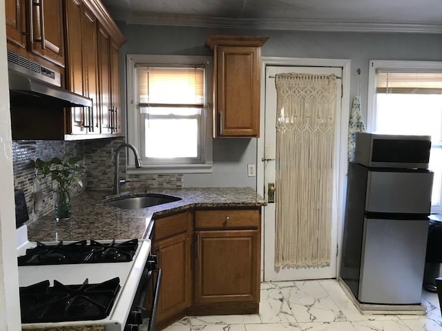 kitchen featuring gas range gas stove, sink, backsplash, stainless steel fridge, and exhaust hood