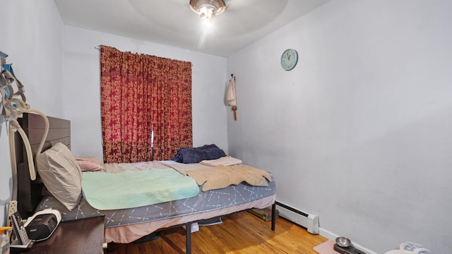 bedroom featuring hardwood / wood-style floors, ceiling fan, and baseboard heating