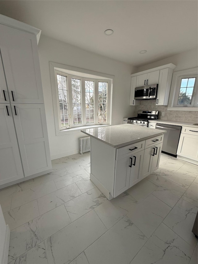 kitchen featuring a kitchen island, radiator, tasteful backsplash, white cabinetry, and stainless steel appliances