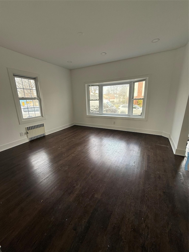 empty room featuring radiator and dark wood-type flooring