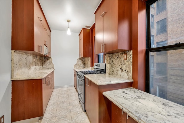 kitchen with decorative backsplash, decorative light fixtures, light stone counters, and stainless steel range with gas stovetop