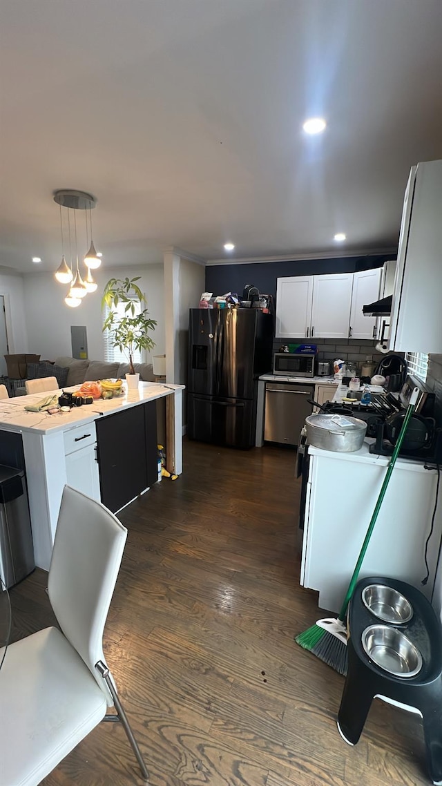 kitchen with pendant lighting, white cabinetry, dark hardwood / wood-style flooring, stainless steel appliances, and backsplash