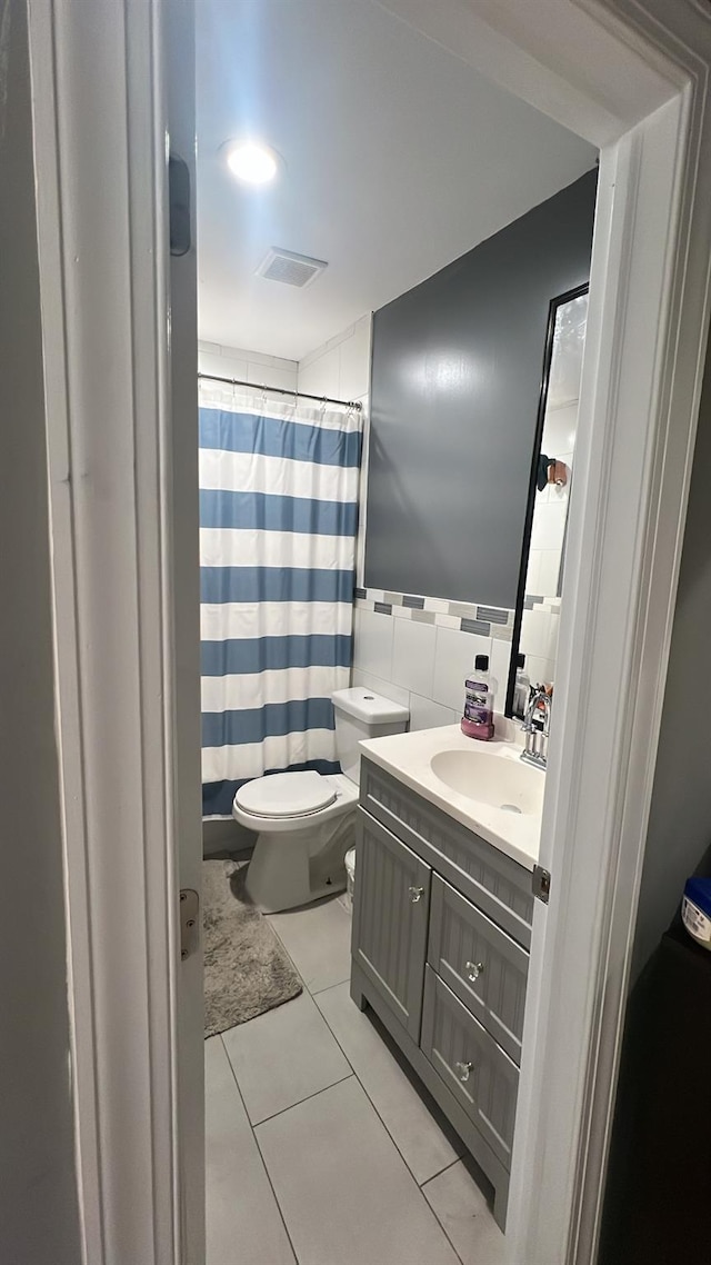 bathroom with toilet, tile patterned flooring, tile walls, and vanity