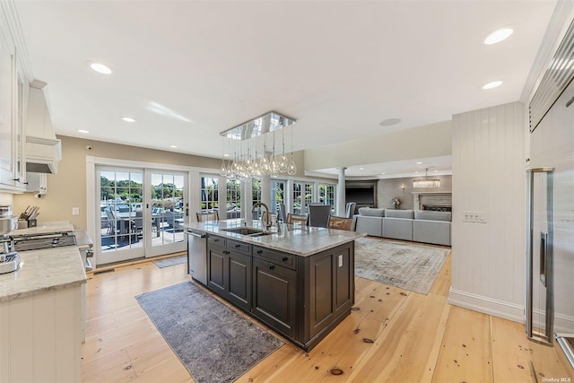 kitchen with white cabinets, stainless steel dishwasher, light stone counters, dark brown cabinetry, and sink