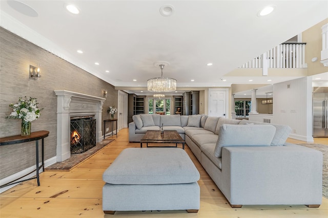 living room with ornamental molding, a chandelier, and light hardwood / wood-style flooring