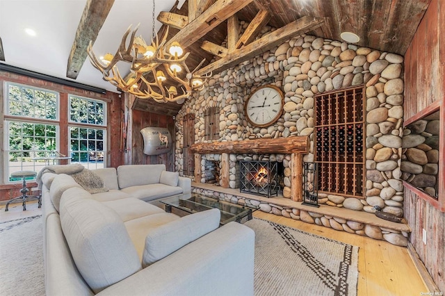 living room featuring hardwood / wood-style floors, a chandelier, vaulted ceiling with beams, and a stone fireplace