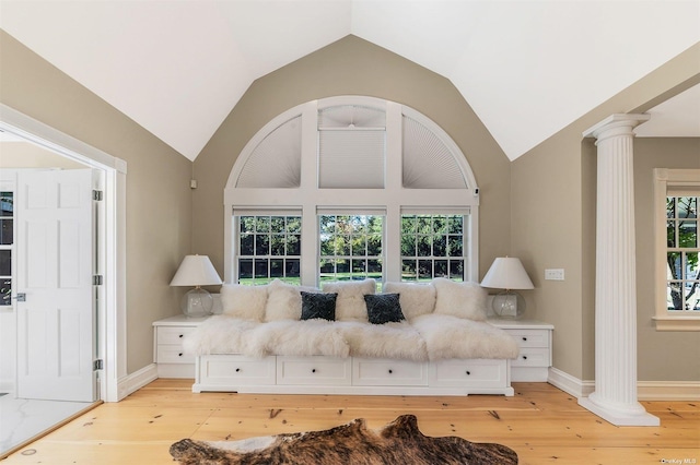 living area featuring lofted ceiling, light hardwood / wood-style flooring, and decorative columns