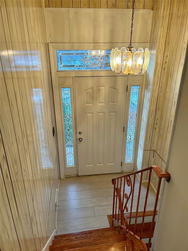 foyer with hardwood / wood-style flooring, a chandelier, and wood walls