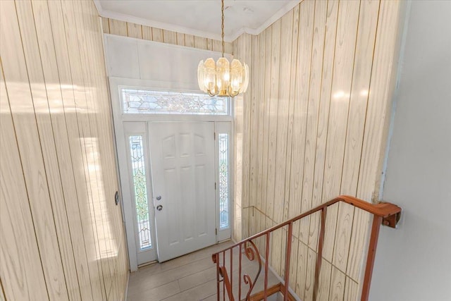 foyer with a notable chandelier, light wood-type flooring, and crown molding