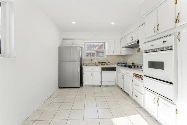 kitchen with under cabinet range hood, stainless steel appliances, a sink, white cabinetry, and light countertops