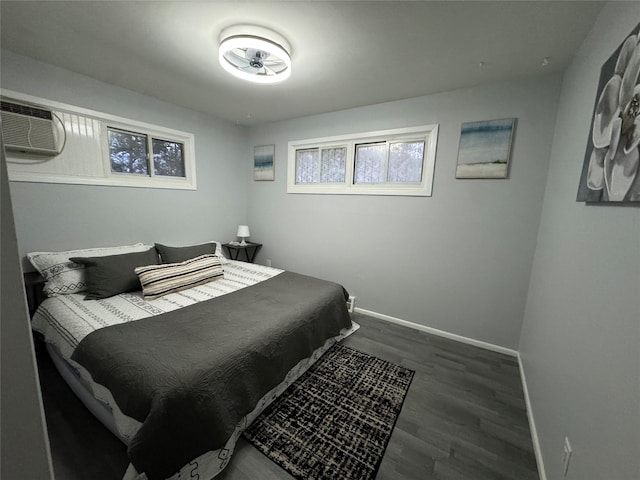 bedroom with dark hardwood / wood-style floors and an AC wall unit