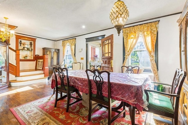 dining room with a textured ceiling, hardwood / wood-style flooring, an inviting chandelier, and crown molding