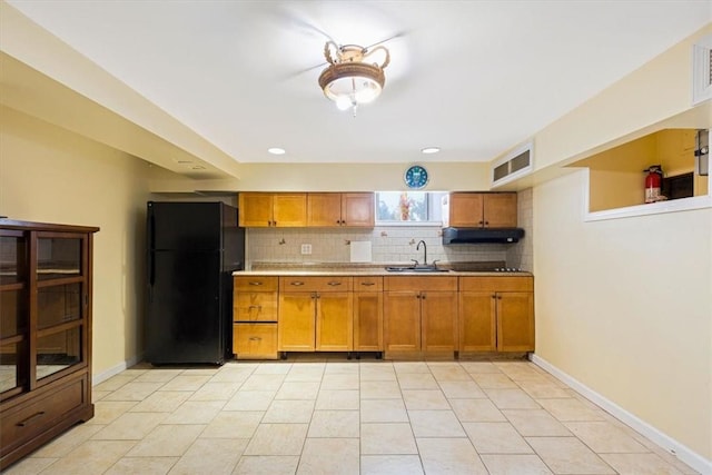 kitchen featuring black refrigerator, decorative backsplash, light tile patterned flooring, and sink