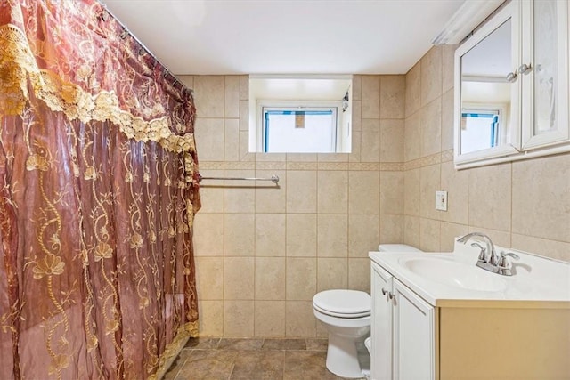 bathroom with tile patterned floors, vanity, tile walls, and toilet