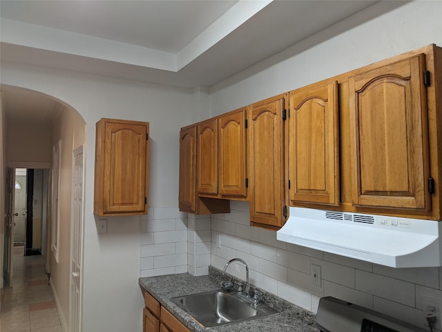 kitchen featuring light tile patterned floors, sink, exhaust hood, and tasteful backsplash