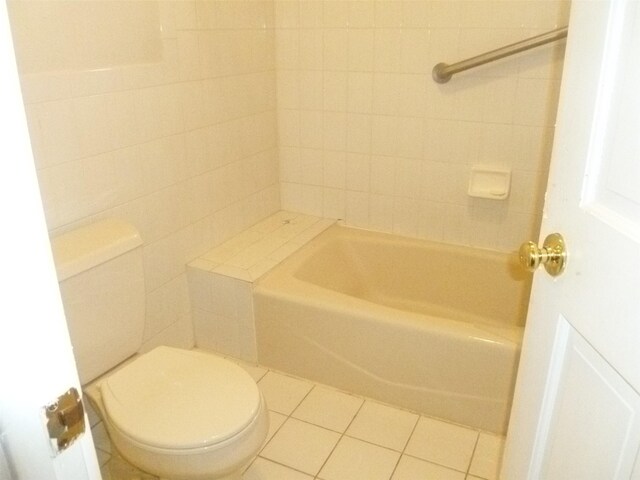 bathroom featuring toilet, tile patterned floors, and tile walls