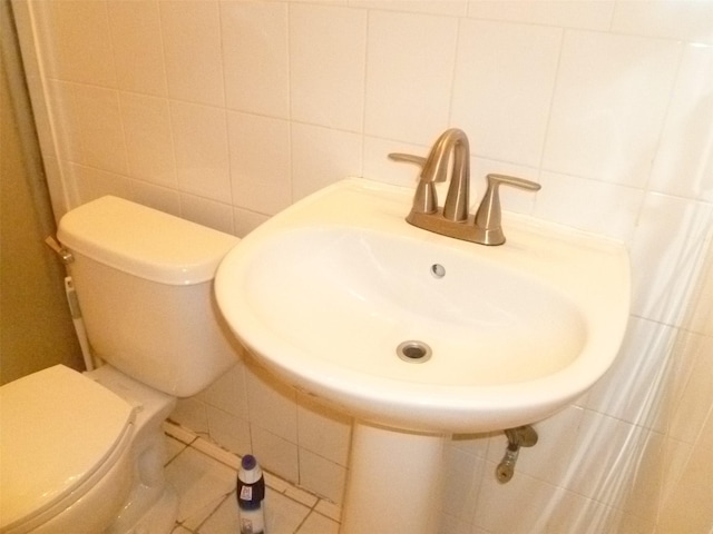 bathroom featuring decorative backsplash, toilet, tile walls, and sink