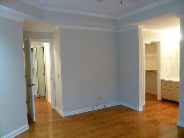 unfurnished bedroom with hardwood / wood-style floors, crown molding, and a spacious closet