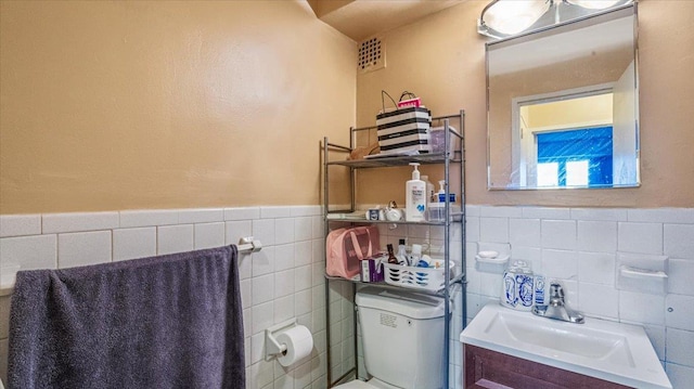 bathroom with vanity, toilet, and tile walls