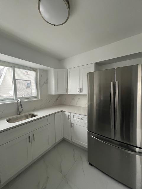 kitchen with stainless steel fridge, tasteful backsplash, white cabinetry, and sink