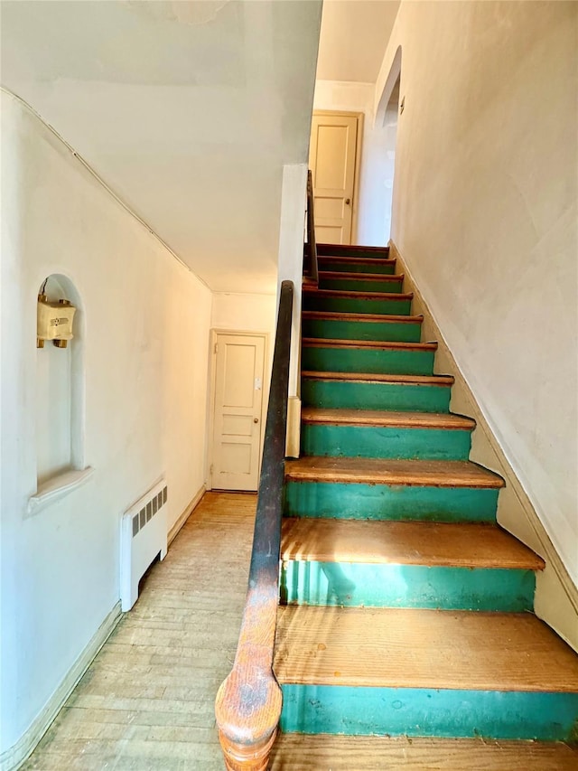 staircase with hardwood / wood-style floors and radiator