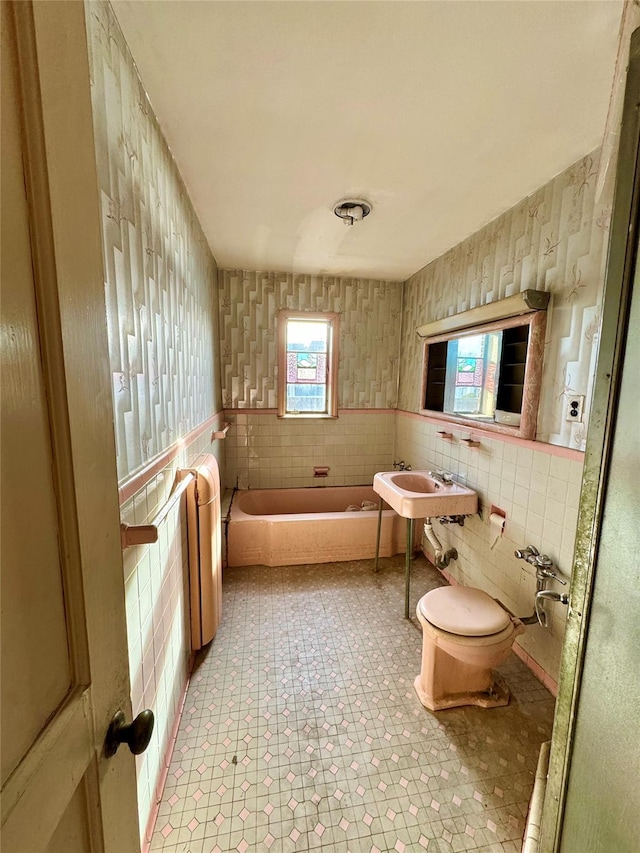 bathroom featuring a bathing tub, toilet, and sink