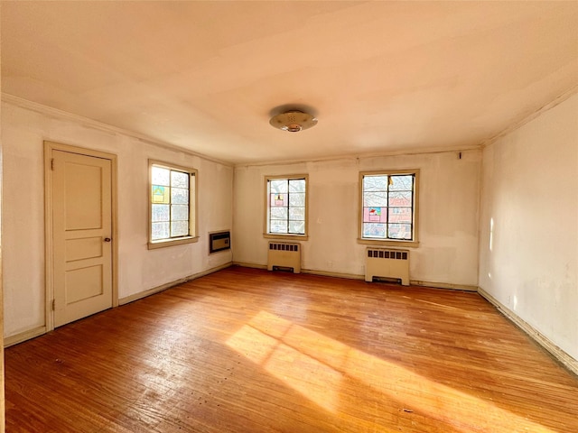 empty room featuring radiator and hardwood / wood-style floors