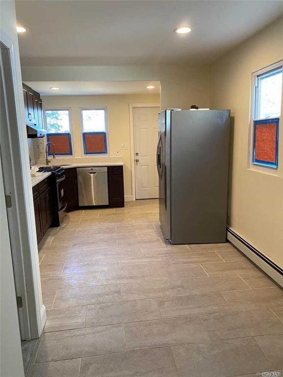 kitchen featuring appliances with stainless steel finishes, tasteful backsplash, dark brown cabinetry, sink, and a baseboard radiator