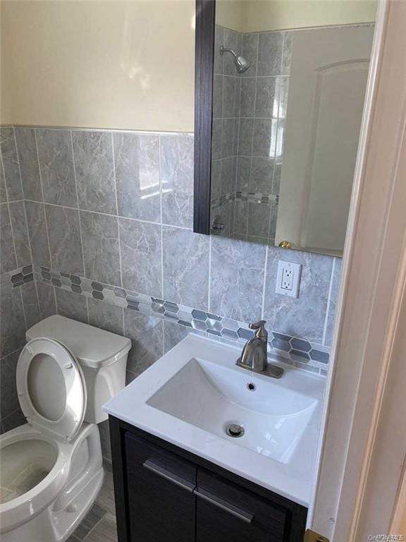 bathroom featuring vanity, tile walls, and toilet