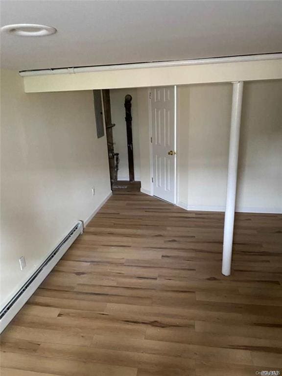 basement featuring wood-type flooring and a baseboard heating unit