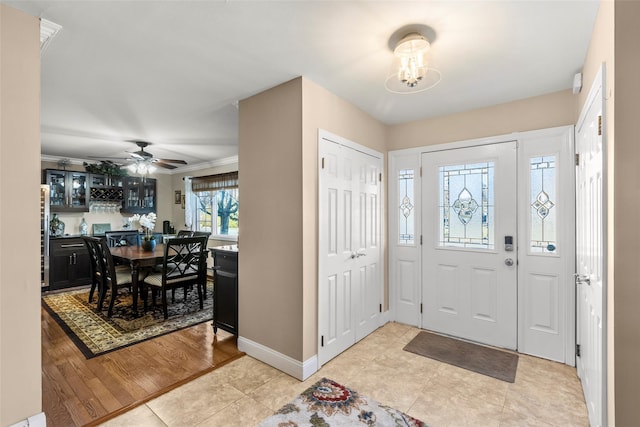 entryway featuring an inviting chandelier, light tile patterned floors, and crown molding