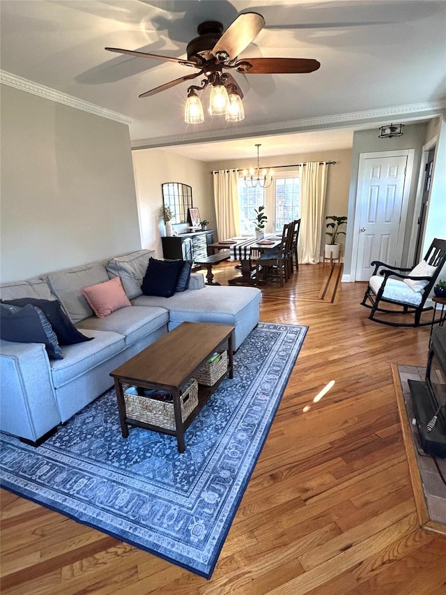 living room featuring ceiling fan with notable chandelier, hardwood / wood-style flooring, and crown molding