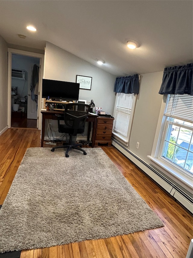 office with hardwood / wood-style floors, lofted ceiling, an AC wall unit, and a baseboard radiator