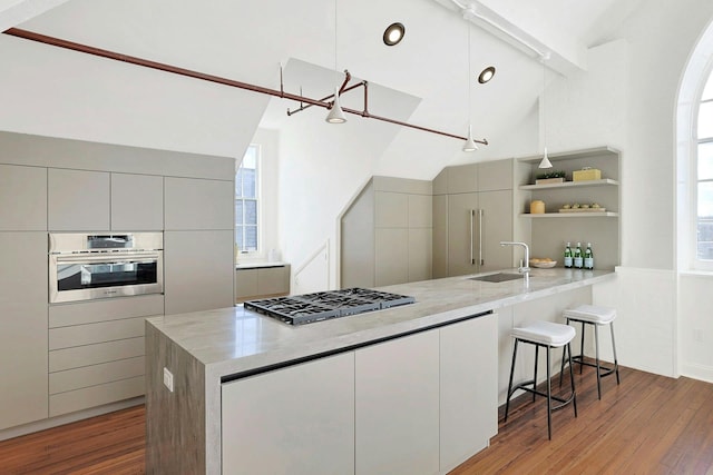 kitchen with appliances with stainless steel finishes, kitchen peninsula, a breakfast bar, sink, and lofted ceiling