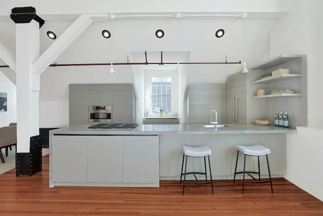 kitchen featuring sink, a kitchen bar, kitchen peninsula, gray cabinets, and beam ceiling