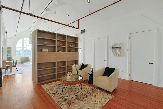 sitting room with a high ceiling, wood-type flooring, and radiator