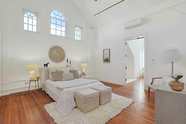 bedroom featuring high vaulted ceiling, an AC wall unit, and hardwood / wood-style floors