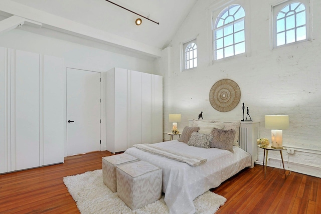 bedroom featuring high vaulted ceiling and hardwood / wood-style flooring