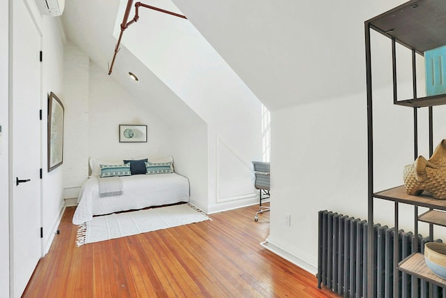 bedroom featuring lofted ceiling, hardwood / wood-style flooring, a wall mounted AC, and radiator