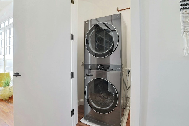 laundry room with hardwood / wood-style flooring and stacked washer / dryer