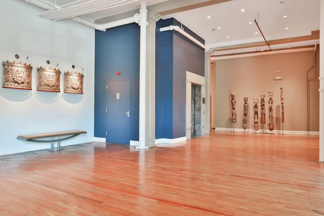 interior space featuring a high ceiling, decorative columns, and light hardwood / wood-style flooring