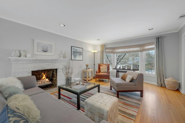 living room featuring crown molding, a fireplace, and light hardwood / wood-style flooring