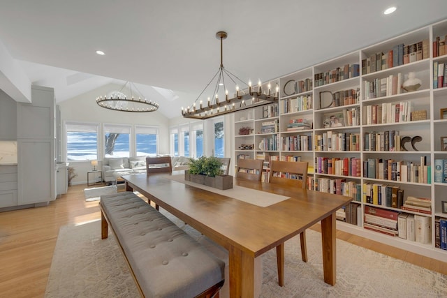 dining room with an inviting chandelier, vaulted ceiling, and light wood-type flooring