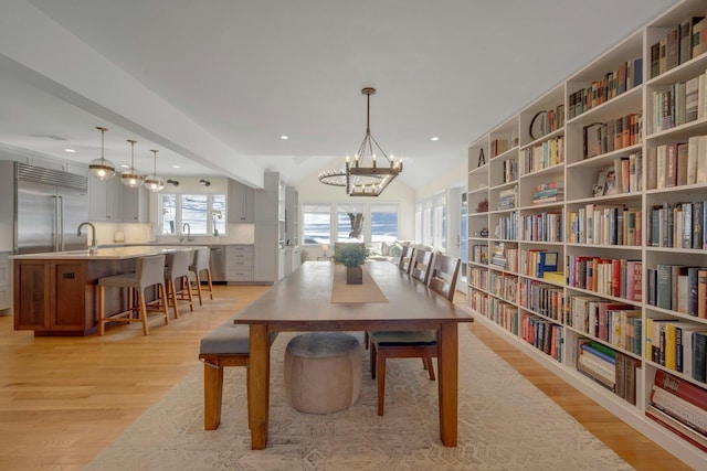 dining room featuring a notable chandelier, sink, and light wood-type flooring