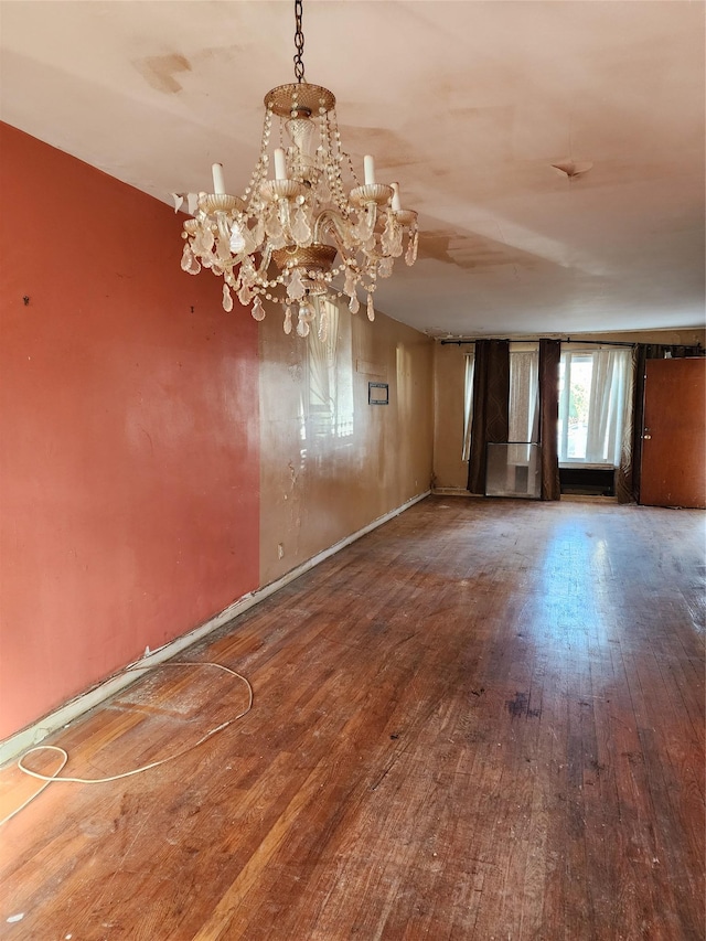 empty room featuring hardwood / wood-style flooring and a chandelier