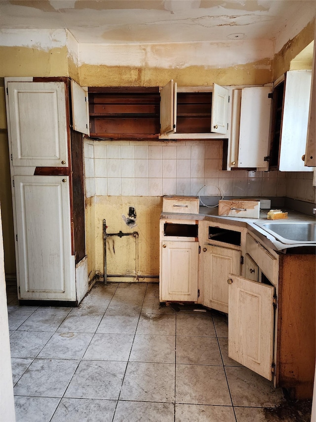 kitchen with backsplash, sink, and light tile patterned flooring