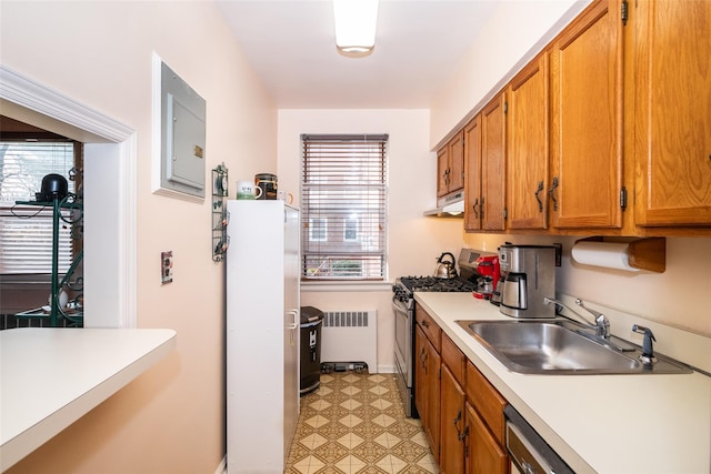 kitchen featuring white fridge, radiator heating unit, sink, and stainless steel range with gas stovetop