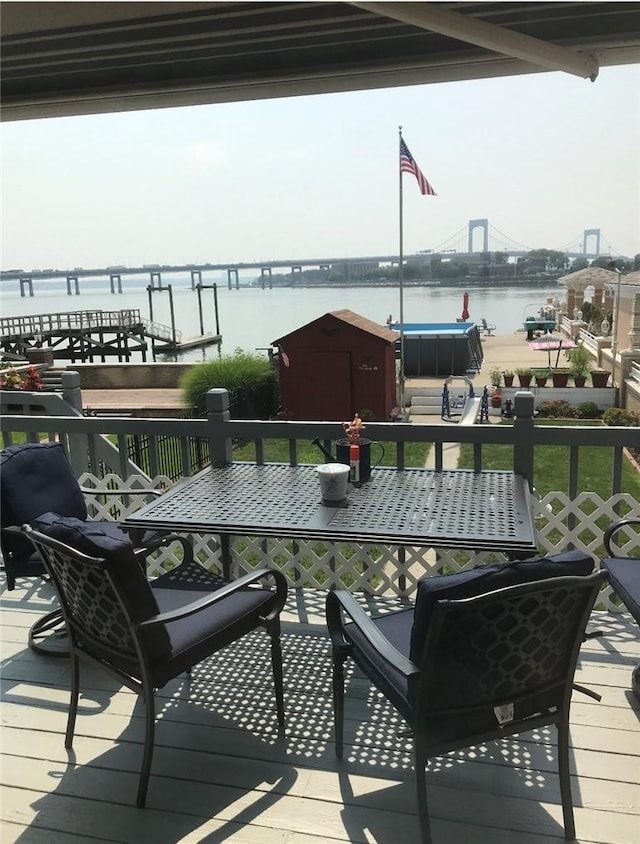 wooden deck with a water view and a storage unit