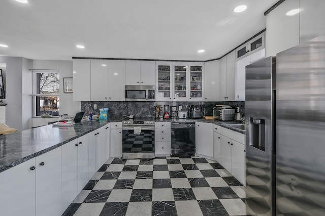 kitchen with white cabinets, dark stone countertops, stainless steel appliances, and tasteful backsplash