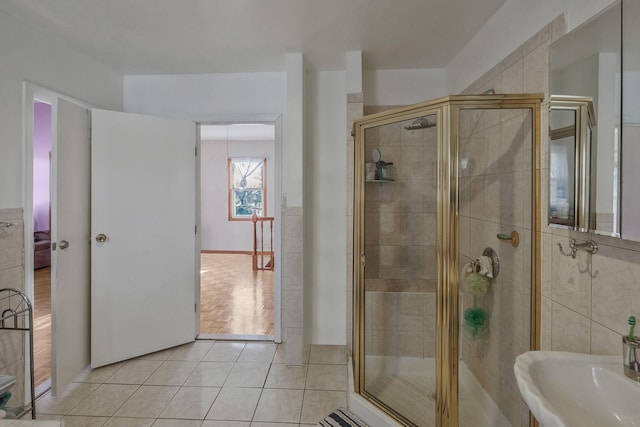 bathroom featuring tile patterned flooring, tile walls, a shower with shower door, and sink